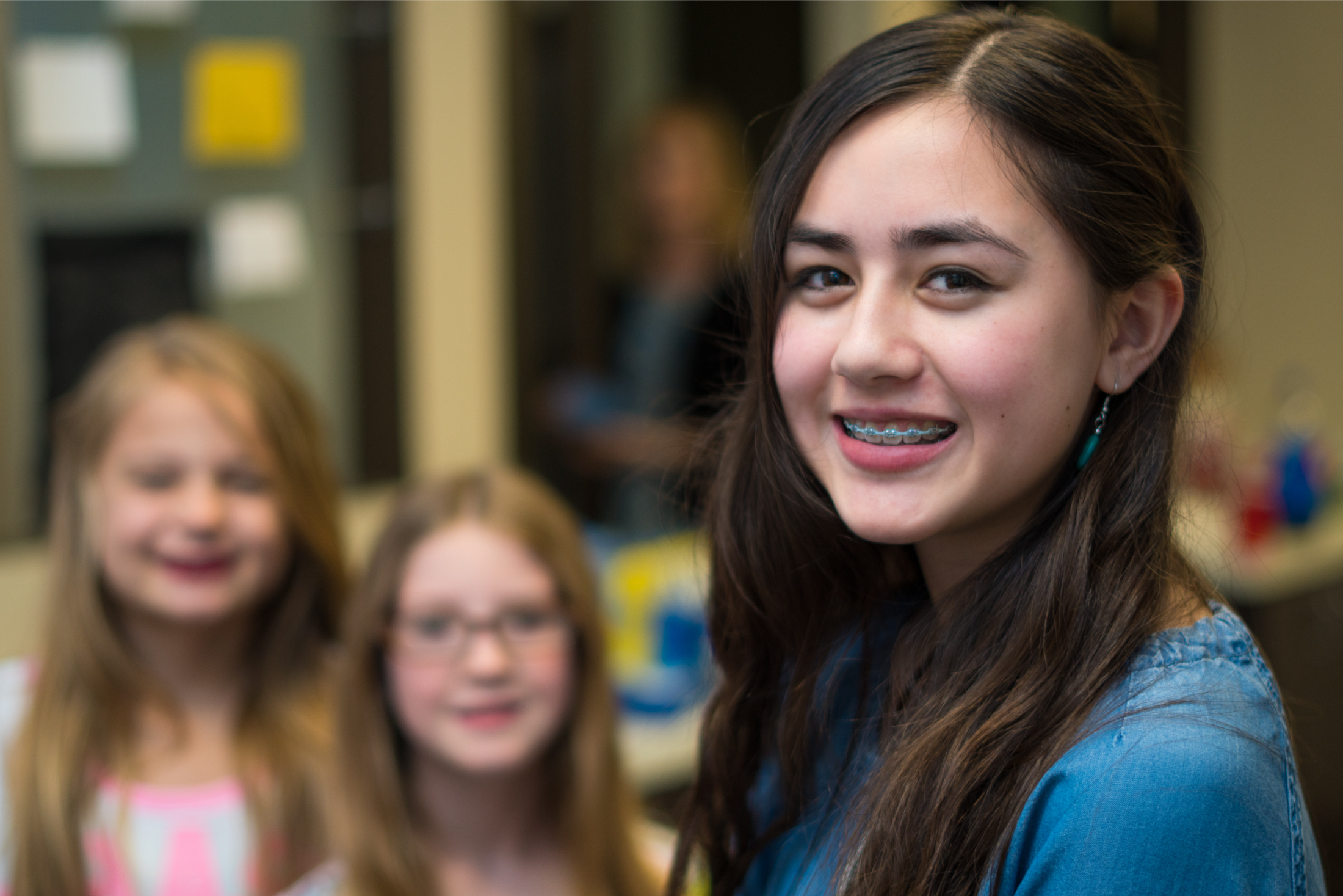 Teen with braces standing with two younger siblings at Smile Makers Orthodontics